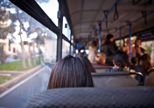 Woman Shown From Behind Sitting On A Bus For Public Transit Woman Shown From Behind Sitting On A Bus For Public Transit